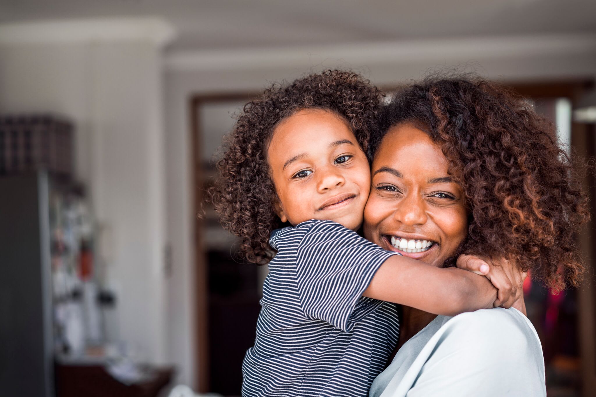 Mother holding young daughter and smiling.